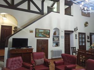 sala de estar con sillas rojas y TV en Cortijo Entresierras en Carcabuey