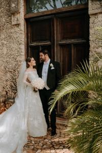 Una novia y un novio parados frente a una puerta en Hacienda Kaan Ac, en Valladolid