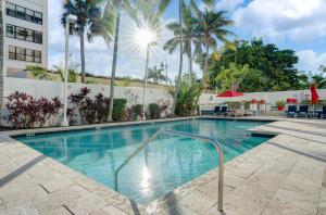 a swimming pool at a hotel with palm trees at Waterview Condo- Spacious 2 bedroom - Central - Steps to Beach in Fort Lauderdale