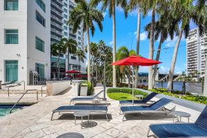 a row of lounge chairs and an umbrella next to a pool at Waterview Condo- Spacious 2 bedroom - Central - Steps to Beach in Fort Lauderdale