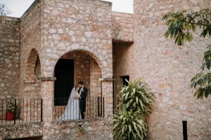 Una novia y un novio de pie en un balcón en Hacienda Kaan Ac, en Valladolid