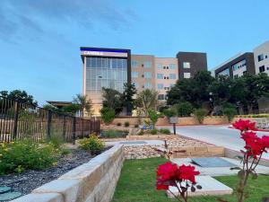 a view of a building with red flowers in front of it at Cambria Hotel Austin Uptown near the Domain in Austin