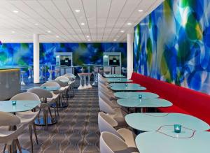 a dining room with tables and chairs and a colorful wall at Prize by Radisson, Hamburg City in Hamburg