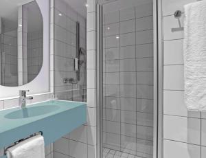 a bathroom with a blue sink and a shower at Prize by Radisson, Hamburg City in Hamburg