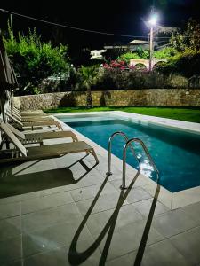un grupo de tumbonas junto a una piscina por la noche en Cost Mari Almyrida New by ZAGO Boutiqe hotels, en Almyrida