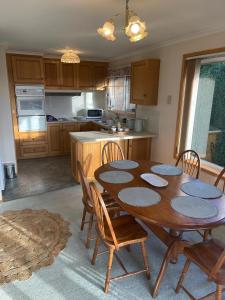 a kitchen with a wooden table with chairs and a tableasteryasteryasteryasteryastery at Sandy Bay Villa in Sandy Bay