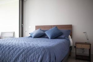 a bedroom with a blue bed with blue pillows at Hermoso departamento amoblado en Concón 2D/2B/1E in Concón