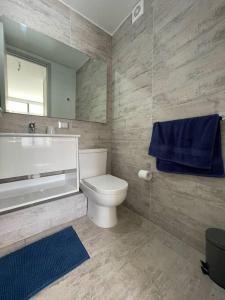 a bathroom with a toilet and a bath tub and a blue towel at Hermoso departamento amoblado en Concón 2D/2B/1E in Concón