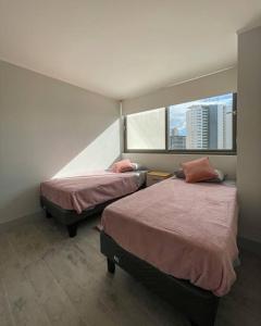 Duas camas num quarto com uma janela em Hermoso departamento amoblado en Concón 2D/2B/1E em Concón