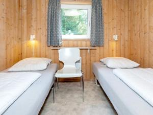 2 camas en una habitación con paredes de madera y ventana en Three-Bedroom Holiday home in Fjerritslev 21 en Torup Strand