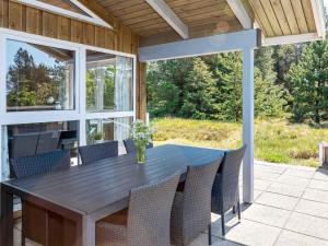 comedor al aire libre con mesa de madera y sillas en Three-Bedroom Holiday home in Fjerritslev 21 en Torup Strand