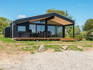 a small black house with a roof on a field at 6 person holiday home in Rønde-By Traum in Rønde