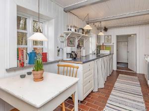 cocina con armarios blancos, mesa y sillas en Holiday home Bedsted Thy IV, en Bedsted Thy