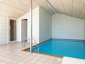 een zwembad in een huis met een tegelvloer bij Holiday home Væggerløse CCXVI in Bøtø By