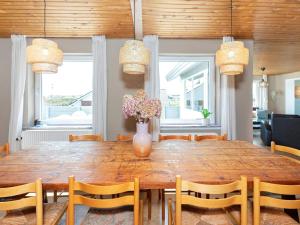 einen Esstisch mit Stühlen und eine Vase mit Blumen in der Unterkunft Holiday Home Sandnæshagevej II in Lild Strand