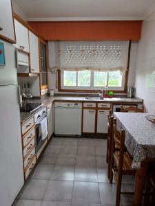 cocina con electrodomésticos blancos y mesa en Apartamento Penedo, camino portugus-CON PLAZA DE GARAJE GRATIS, en Santiago de Compostela