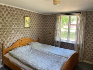 a bedroom with a wooden bed and a window at Cottage with beautiful nature, open landscape, forest and lakes I X I Stuga med fin natur, öppna landskap, skog och sjöar in Tingsryd