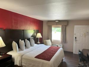 Habitación de hotel con cama y pared roja en Pinetree Inn en Parsons