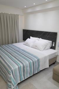 a bedroom with a large bed with a striped blanket at Arpoar Suítes 330 in João Pessoa