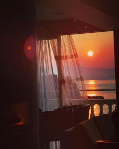 a sunset seen through a window with a curtain at Pontikonisi Hotel & Suites in Perama