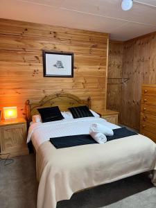 1 dormitorio con 1 cama grande y paredes de madera en Carinya Village Jindabyne en Jindabyne
