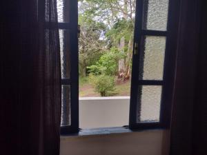 uma janela aberta com vista para um jardim em Casa Jequitiba Quartos Mobiliados em Macaé