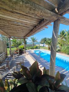 a swimming pool with a wooden pergola at Casarão de frente para a lagoa de Praia Seca in Praia Sêca