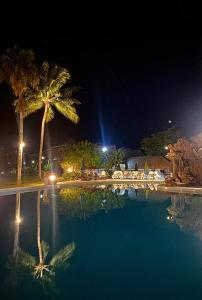 a swimming pool with palm trees at night at Royal Tahitien in Papeete