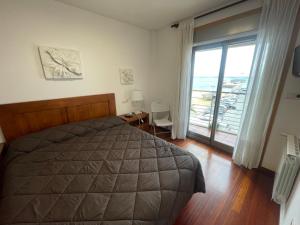 a bedroom with a bed and a large window at PLAYA 10 METROS in Bueu