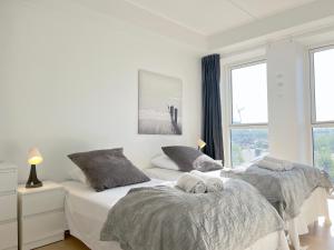 a white bedroom with two beds and a window at Modern Spacious 3 Bedroom Apartment At Ricahrd Mortensens Vej With Balcony Close To The Royal Arena And Fields in Copenhagen