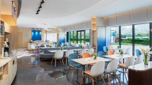 ein Restaurant mit Tischen, Stühlen und Fenstern in der Unterkunft Holiday Inn Express Dalian Golden Pebble Beach, an IHG Hotel in Dalian