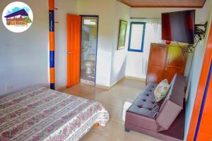 a bedroom with a bed and a couch and a television at Finca Turistica La Betulia Sevilla in Sevilla