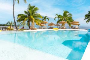 a swimming pool with palm trees and umbrellas at Cook's Bay Hotel & Suites in Paopao