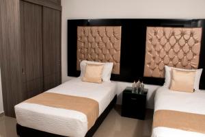 a bedroom with two beds and a headboard at ALESOMAYA APARTHOTEL in Cali