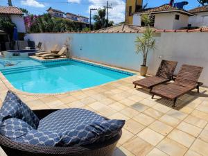 a swimming pool with two chairs next to a house at Pousada Costa Del Sol in Búzios