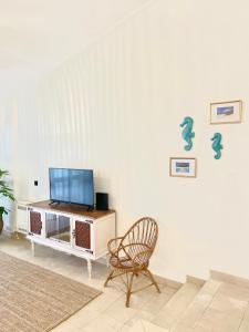 a living room with a chair and a tv on a wall at Detailed Villa - In Vilamoura's Heart in Vilamoura
