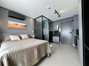 a bedroom with a large bed and a bathroom at Studio em frente a praia do Bessa in Tambaú