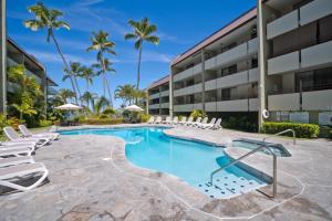 a swimming pool with lounge chairs and a building at Kilokilo Kona at Magic Sands Beach in Kailua-Kona