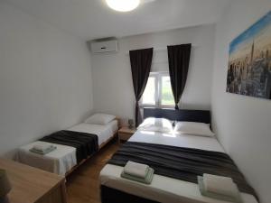 2 Betten in einem kleinen Zimmer mit Fenster in der Unterkunft Apartments by the sea Kastel Stafilic, Kastela - 21087 in Kaštela