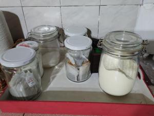 ein Regal mit vier Gläsern Milch im Kühlschrank in der Unterkunft AMALUR in Sañogasta