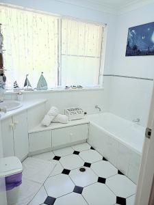 Baño blanco con bañera y lavamanos en Kincumber Guest Suite en Kincumber