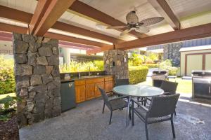 a patio with a table and chairs and a stone wall at Kilokilo Kona at Magic Sands Beach in Kailua-Kona