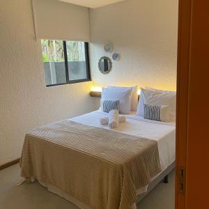 1 dormitorio con 1 cama blanca grande y 2 almohadas en Villa Kamby Milagres B004, en São Miguel dos Milagres