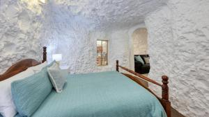 a bedroom with a bed in a stone wall at Desert Hideaway - Underground living - White Cliffs in White Cliffs