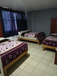 a room with three beds with purple covers on them at HOTEL PUERTO MEXICO 2 in Mexico City