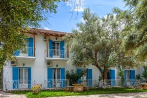 a house with blue shutters and a tree at Oceanis Rooms in Mikros Gialos