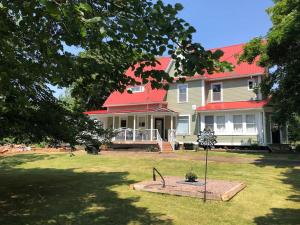 a large house with a red roof and a yard at The Doctors Inn New Brunswick in Cape Tormentine
