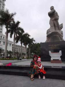 Nhà nghỉ Hằng Nga في دونغ هوي: امرأة وطفل يجلسون أمام تمثال