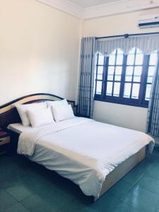 een slaapkamer met een groot bed met witte lakens en kussens bij Hung Vuong Hotel in Pleiku