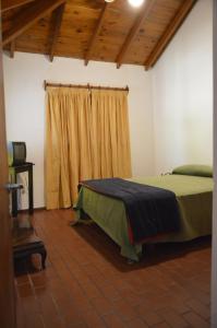 a bedroom with a bed and a window with a curtain at Cabañas Tres Ríos Vacacional in Villa Cura Brochero
